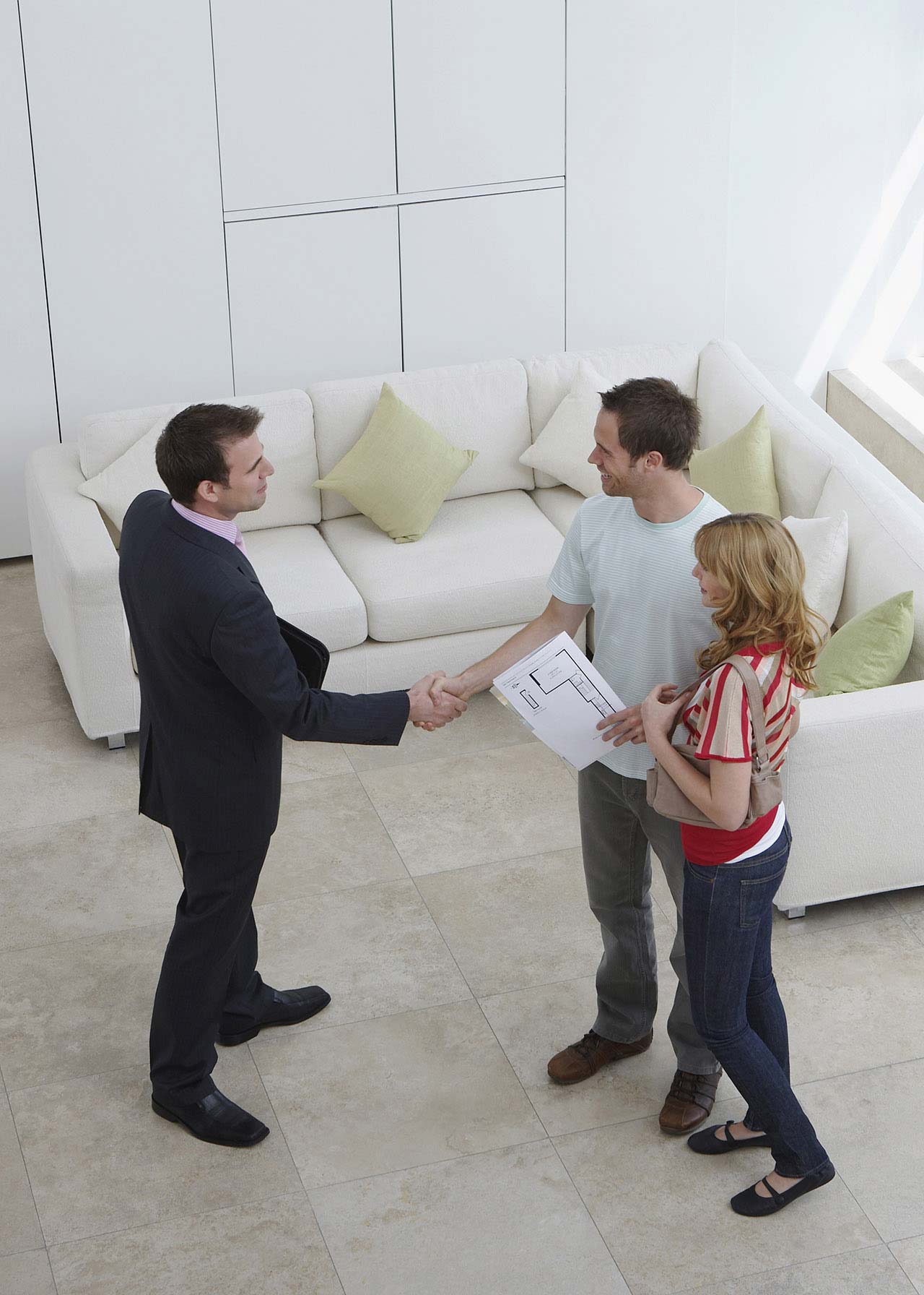 Real estate agent shaking hands with a couple in a new home