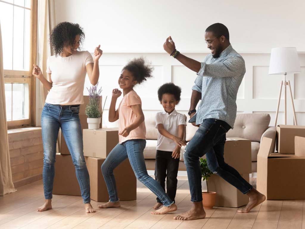 Family dancing as they move into a new home